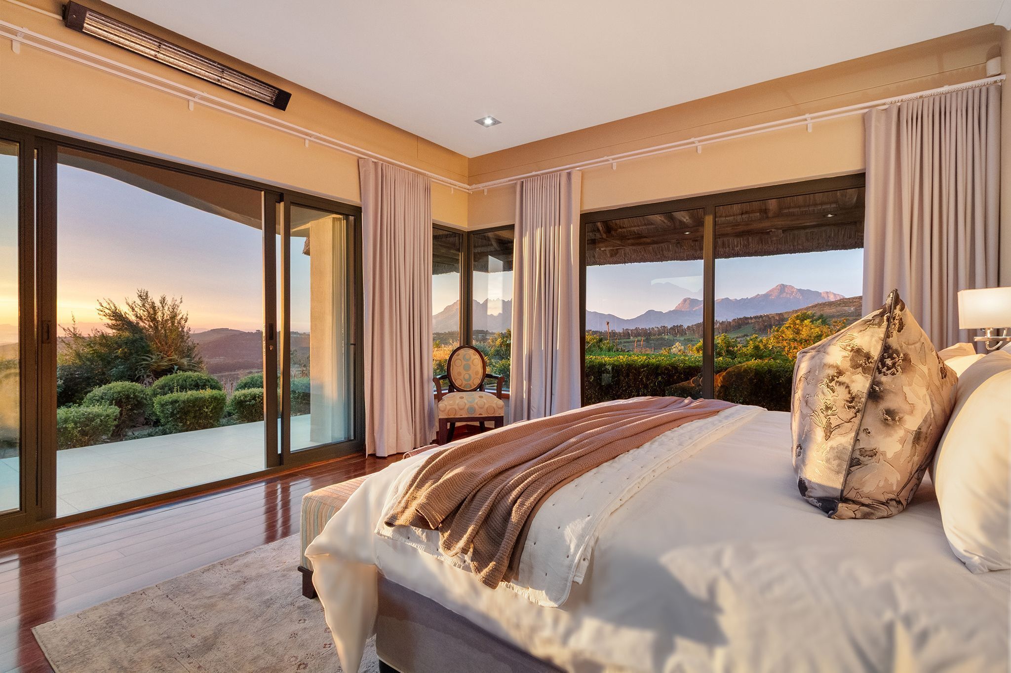 A spacious bedroom with a large bed, a view of mountains, and a sliding glass door to the outdoors.
