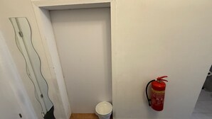 A hallway with a white door, a white bucket, and a red fire extinguisher mounted on the wall. - Cozy 1BR Apt Walk to Westbahnhof (Vienna)