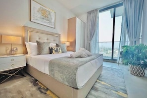 Une chambre d’hôtel moderne avec un grand lit, une table de chevet, une commode, une fenêtre avec des rideaux et une vue sur la ville.