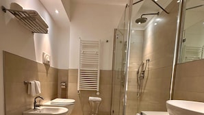Een moderne badkamer met een douchecabine van glas, twee wastafels en een toilet.