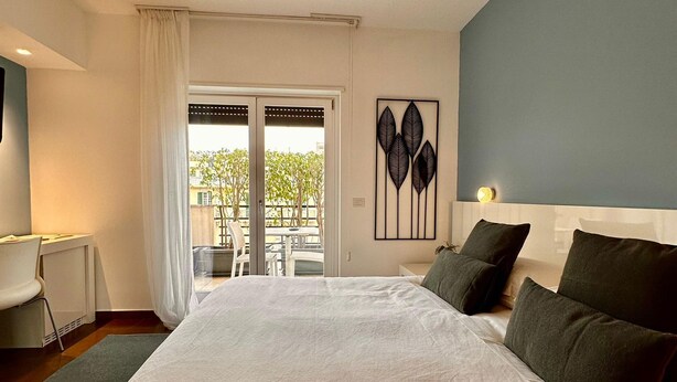 Een slaapkamer met een groot bed, een bureau en uitzicht op de omgeving via een schuifdeur.