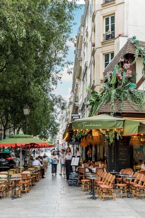 Un café con terraza, un letrero que dice "LE Tambour" y un edificio con balcón.