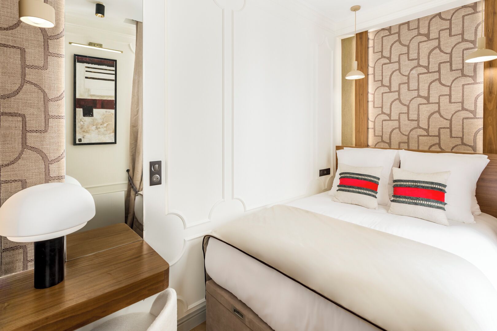 A neatly arranged bedroom with a bed, bedside table, and a hanging light fixture.