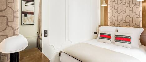 A neatly arranged bedroom with a bed, bedside table, and a hanging light fixture.