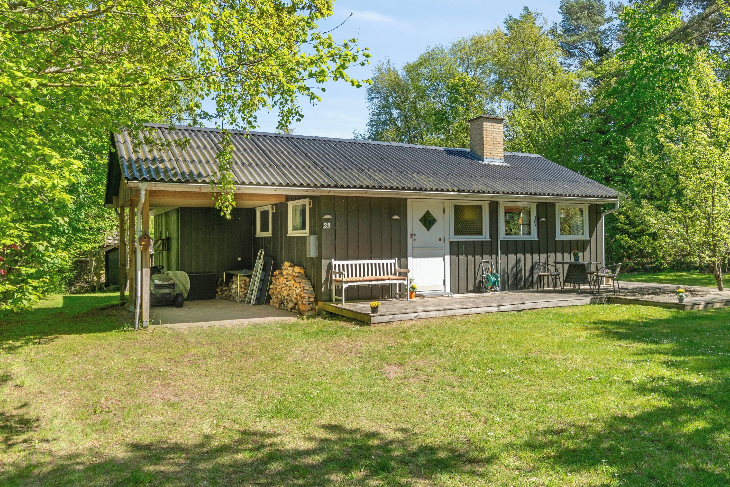A single-story building with a porch, a bench, and a small garden area.