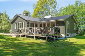 Ein Haus mit Veranda, einer Hängematte und einer Terrasse.
