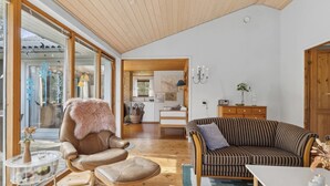 Un amplio espacio de estar con un sillón de cuero marrón, un sofá a rayas y una mesa de comedor de madera.