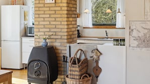 Una cocina con pared de ladrillo, estufa a gas, microondas y una ventana con cortinas.