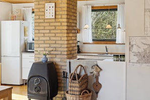 A kitchen with a brick wall, a gas stove, a microwave, and a window with curtains.