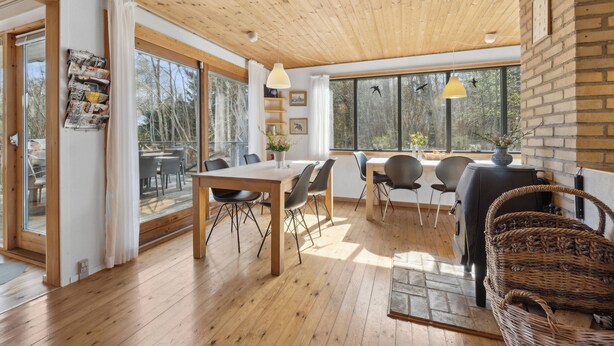Un interior moderno con suelos de madera, zona de comedor y ventanas amplias.