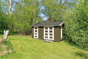 A small wooden cabin with a sloped roof, a front porch, and a door with glass panels.
