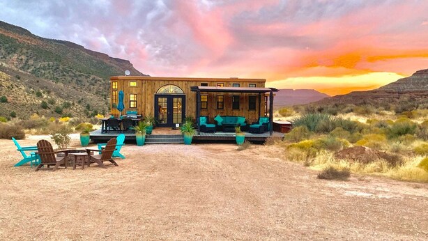 Une cabane en bois dotée d’une véranda, d’un espace salon extérieur et surplombant un paysage désertique.