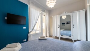 Un dormitorio con cama, armario, televisor y ventana con cortinas.