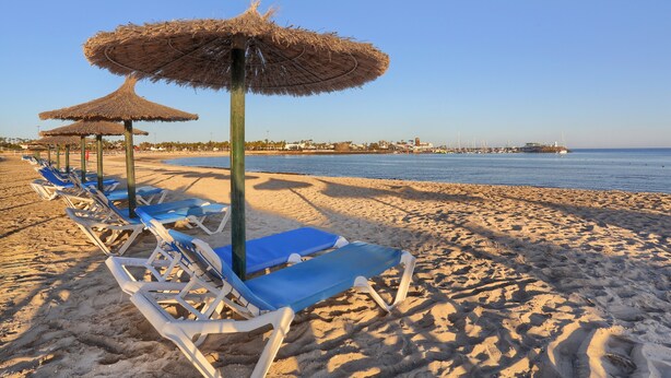 A beach with rows of sun loungers and thatched umbrellas. - Holiday Home 'Casa Vista Golf' with Sea View, Shared Pool & Wi-Fi (Castillo Caleta de Fuste)