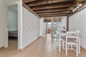 Une pièce comprenant un lit, une table à manger avec des chaises, un coin cuisine et un plafond en bois.