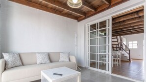 A living room with a sofa, a coffee table, and a sliding glass door leading to a staircase. - Holiday Home 'Casa Vista Golf' with Sea View, Shared Pool & Wi-Fi (Castillo Caleta de Fuste)