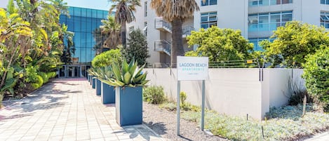 A pathway leading to a building with a sign indicating 'LAGOON BEACH APARTMENTS' in Cape Town.