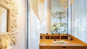A wooden desk with a window view, decorative wall art, and a hanging light fixture. - Elite condo, Sea View at Batumi Botanical Gardens interior by 3-Kopheli (Batumi)