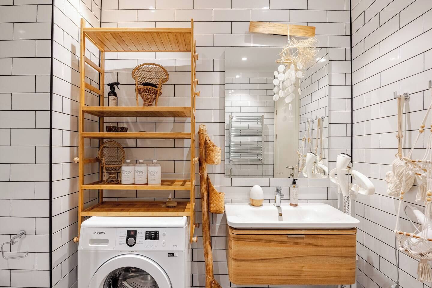 A modern bathroom with a washing machine, wooden shelves, a sink with a mirror, and decorative wall elements.