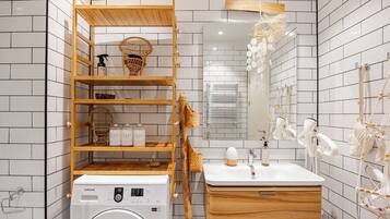 A modern bathroom with a washing machine, wooden shelves, a sink with a mirror, and decorative wall elements.