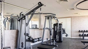A gym with weight machines, a bench, and dumbbells. - Elite condo, Sea View at Batumi Botanical Gardens interior by 3-Kopheli (Batumi)