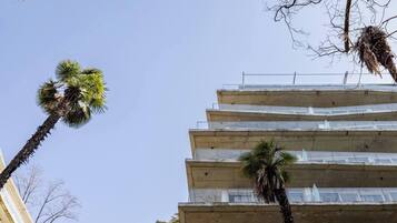 Um edifício de vários andares com varandas e palmeiras.