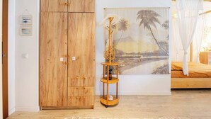 A room with a wooden wardrobe, a painting of a beach scene, and a bed with a canopy. - Elite condo, Sea View at Batumi Botanical Gardens interior by 3-Kopheli (Batumi)