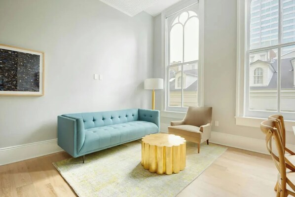 Ein modernes Wohnzimmer mit einem blauen Sofa, einem runden Beistelltisch aus Gold und einem beigeen Sessel.