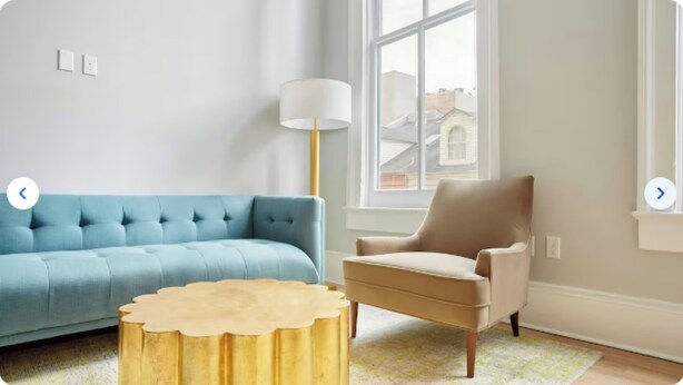 A living room with a blue sofa, a beige armchair, and a gold coffee table.