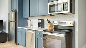 A modern kitchen with blue cabinets, stainless steel appliances, and a white countertop. - Walk to Bourbon St, Riverfront Park, French Qtr | Canal St Stay | The Harlequin (New Orleans)