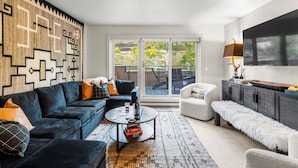 A modern living room with a dark sofa, a white armchair, a coffee table, and a patterned rug.
