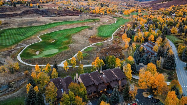 An aerial view of a golf course with houses and trees in autumn colors.