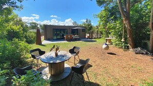 A modern house with a patio area, a round wooden table, and outdoor seating. - Fokkemaat - Modern family home with large garden, close to the beach and town center (Callantsoog)