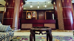 Un hall d’entrée avec un tapis à motifs, un canapé, une table et des colonnes décoratives.