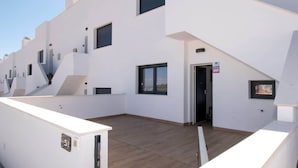 Un immeuble d’appartements moderne, doté d’un toit plat, de nombreux balcons et offrant une vue sur un ciel dégagé.