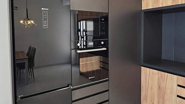A modern kitchen with a built-in microwave, a wooden cabinet, and a dining area with a chandelier.