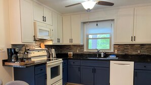 A modern kitchen with white cabinets, a black countertop, a built-in oven, and a dishwasher.