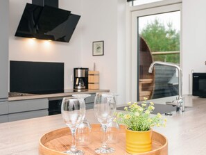 Une cuisine moderne avec un plateau en bois sur lequel sont posés des verres à vin et un pot de fleurs jaune.