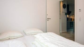 Ein Schlafzimmer mit einem Bett, Kissen und einer Tür zu einem Küchenbereich.