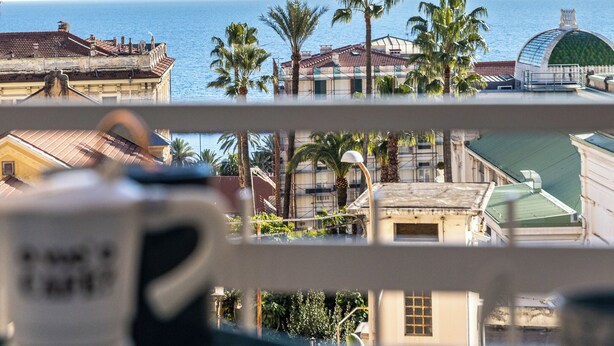 A balcony with a view of the sea, palm trees, and buildings. - Casinò Charme with Terrace by Wonderful Italy (Sanremo)