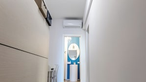 A hallway with a light fixture, a chair, and a counter with a mirror. - Casinò Charme with Terrace by Wonderful Italy (Sanremo)