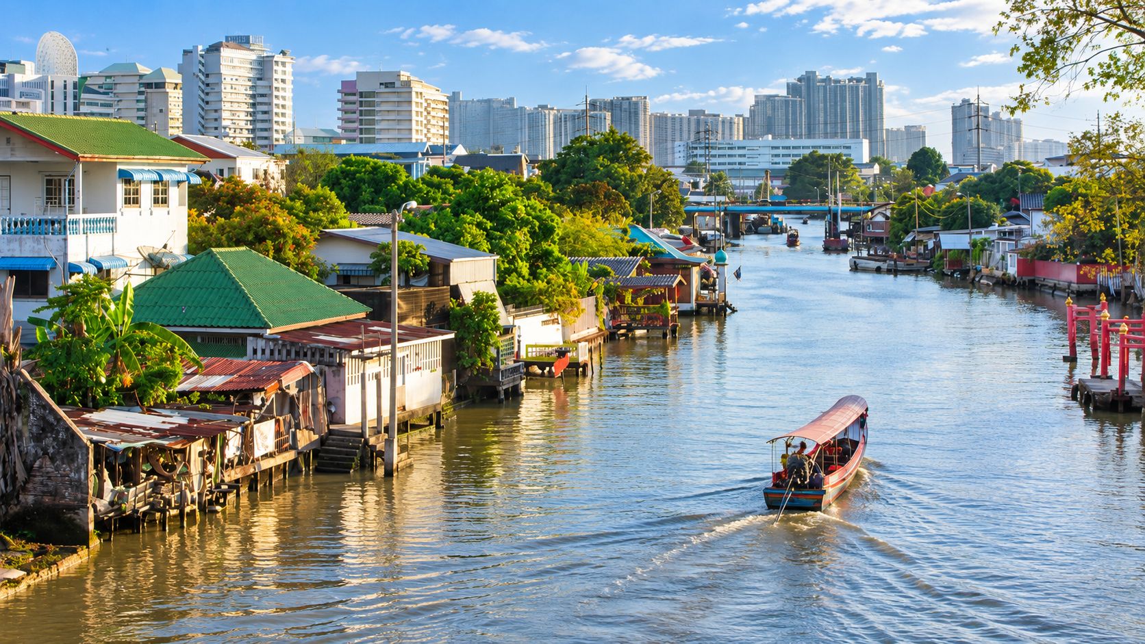 A river with boats, buildings, and a city skyline in the background.