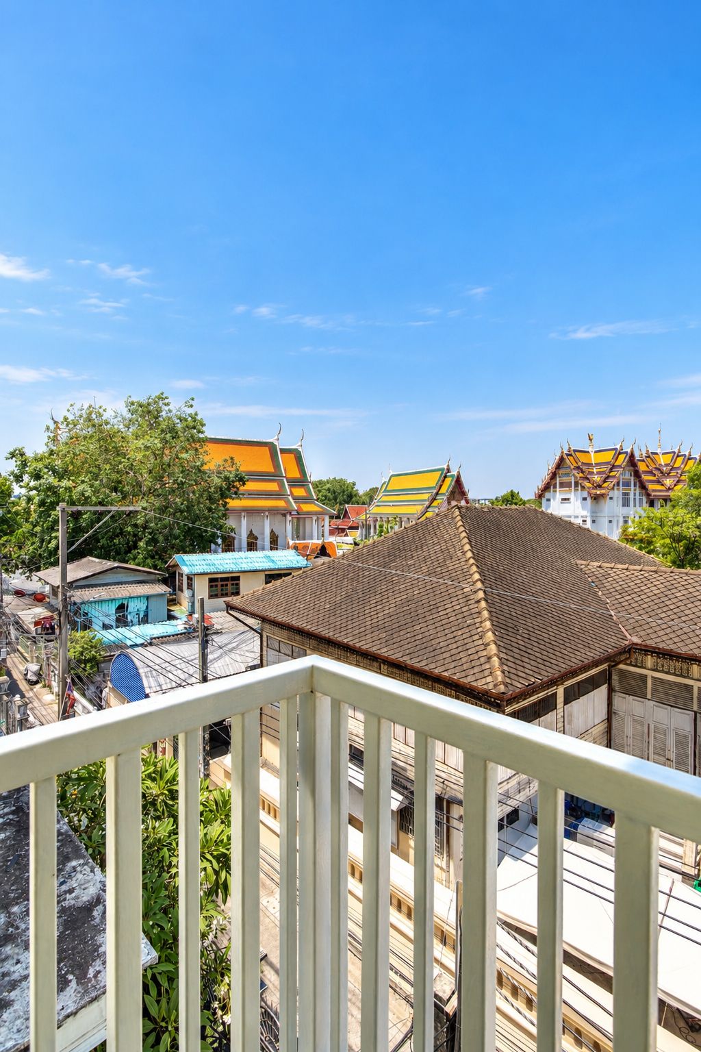 A view from a balcony overlooking traditional buildings with tiled roofs and a clear blue sky.