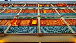 Une façade d’immeuble ornée de nombreuses fenêtres, chacune dotée de volets en bois traditionnels et de motifs verts décoratifs.