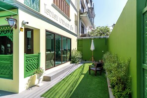 A building with a green exterior, a visible entrance, and a small outdoor seating area with a table and chairs. - Bangluang Boutique Hotel (Bangkok)