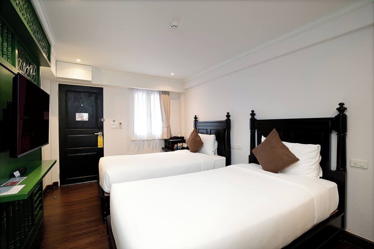 Une chambre d’hôtel avec deux lits, une télévision, un bureau et une porte.