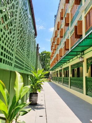 Un estrecho callejón con arquitectura tradicional, con balcones con contraventanas de madera y barandillas de celosía verde.