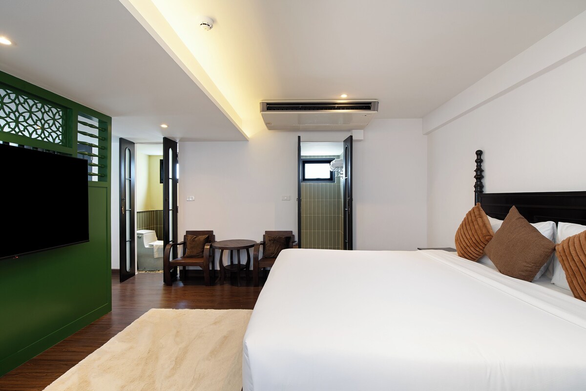 Una habitación de hotel con una cama, televisión, escritorio y silla.
