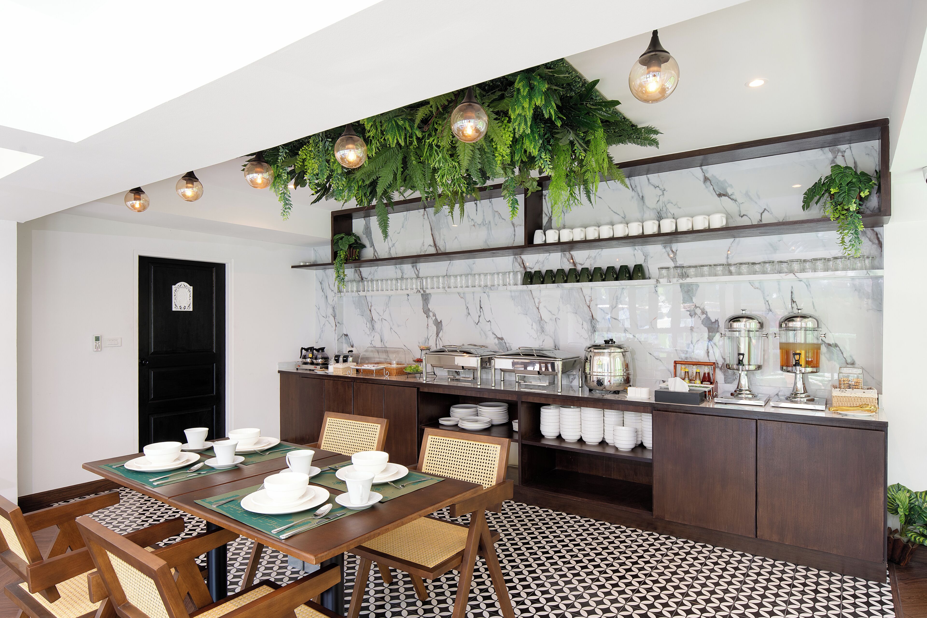 Uma sala de jantar com painel de parede em mármore, buffet e plantas penduradas.