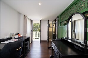 A hotel room with a desk, a chair, a bed, a window, and a door leading to a balcony.